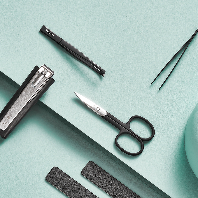 Set of TRUYU Tools on light blue background. Includes, Slant Tip Tweezer, Point Tip Tweezer, Black Curved Nail Scissors and Toenail Clipper.