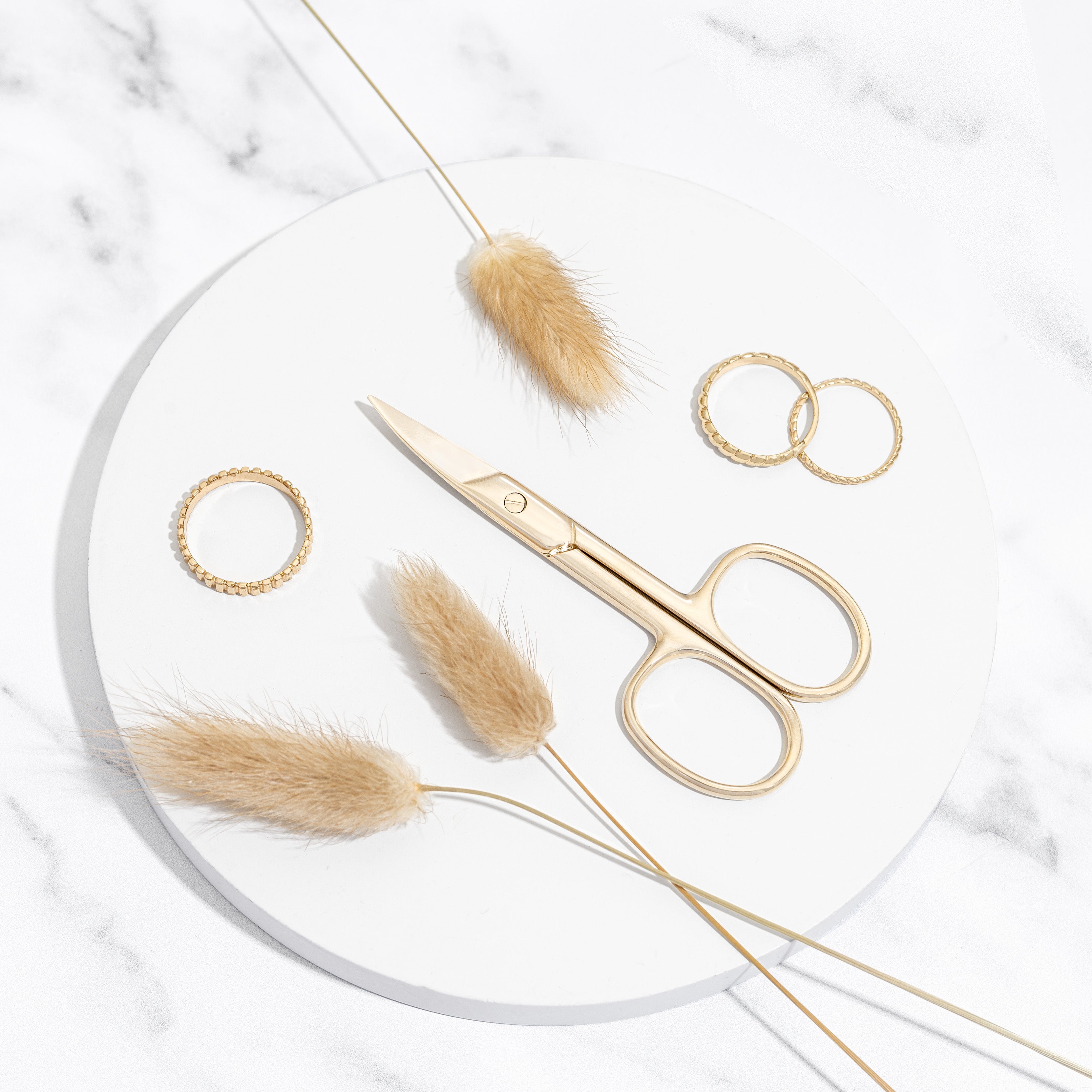 TRUYU Gold Nail Scissor on marble plate and rings. Stylised image.