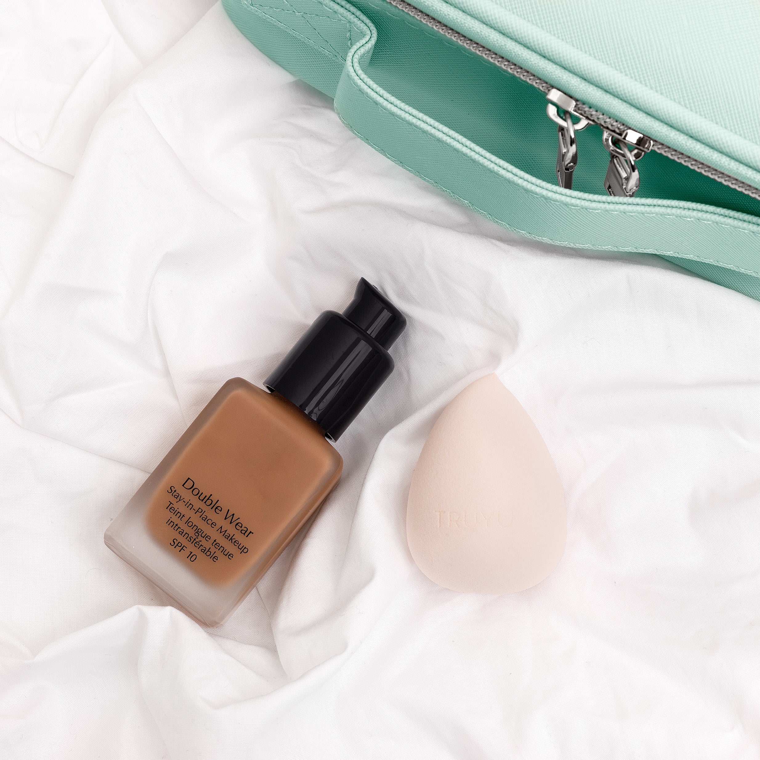 TRUYU Deluxe Blending Egg Sponge with make up and make up bag on soft surface.