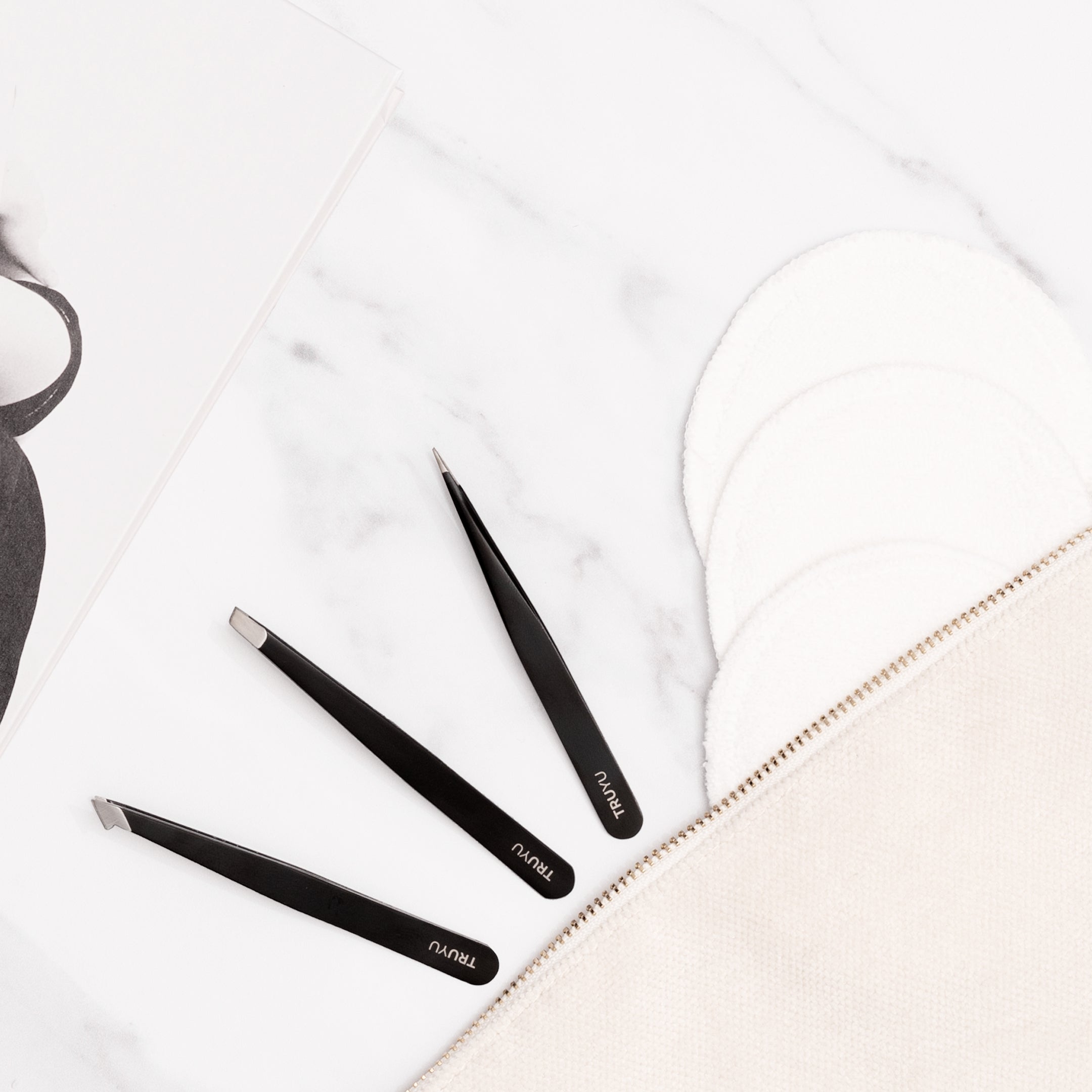 TRUYU Black Tweezer Trio. Slant, Combo and Point Tips. on marble background with facial cleansing cloths in stylised background.