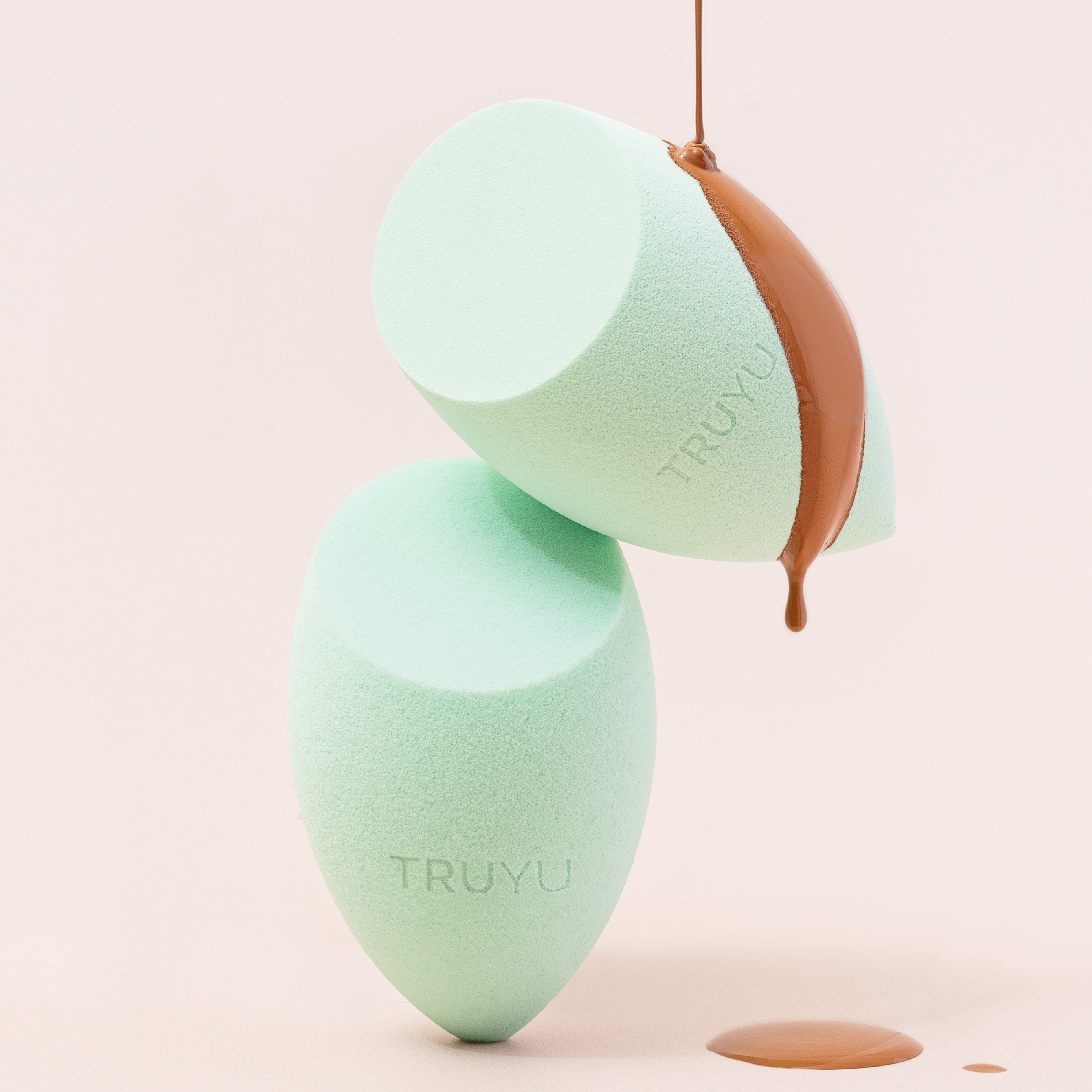 TRUYU Angled Blending Sponge. Styled image showing two sponges on top of each other with foundation dripping off sponge..