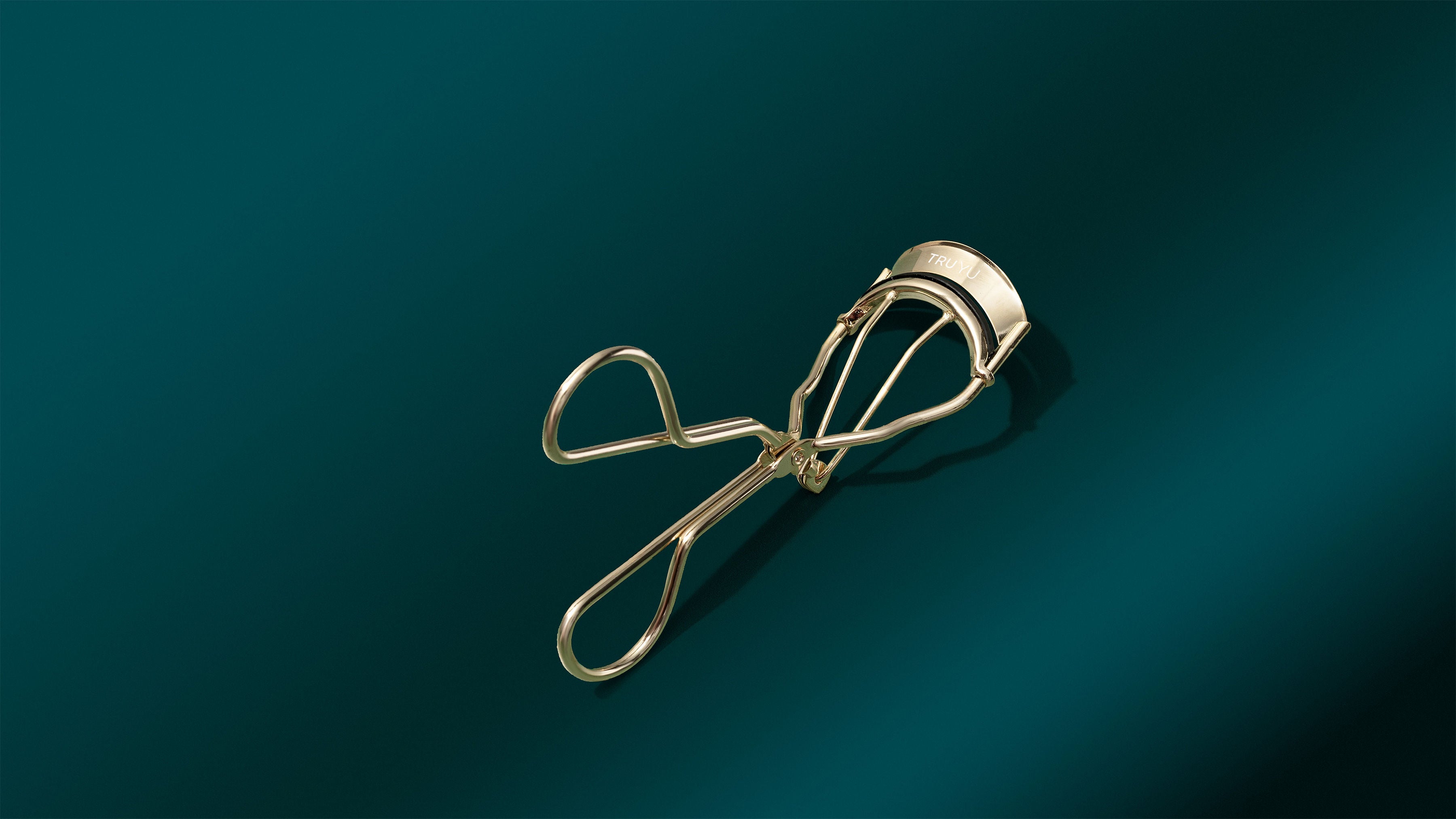 TRUYU Curl Wonder Eyelash Curler on a teal backround