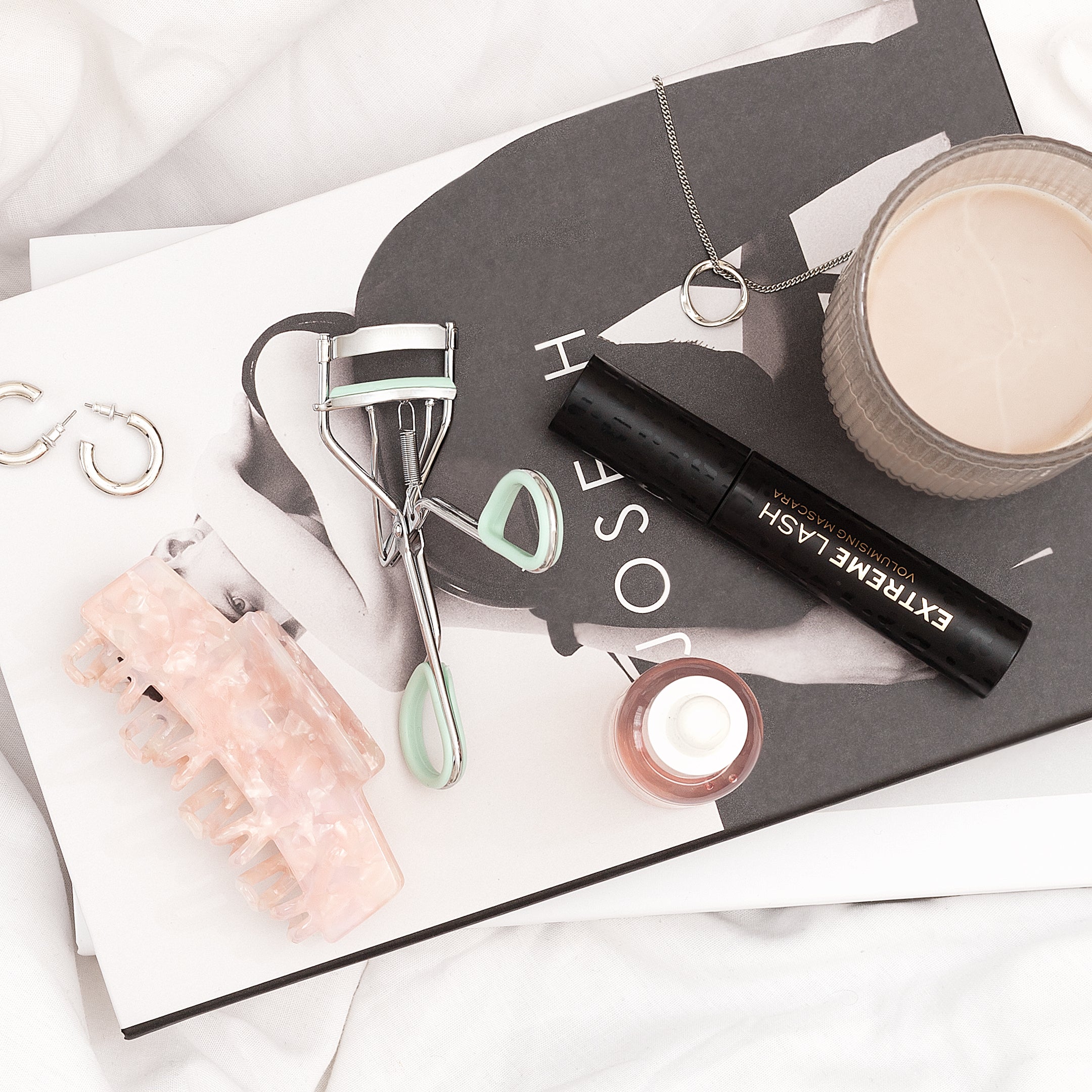 TRUYU Silver Spring Loaded Eyelash Curler on book and mascara in stylised image.