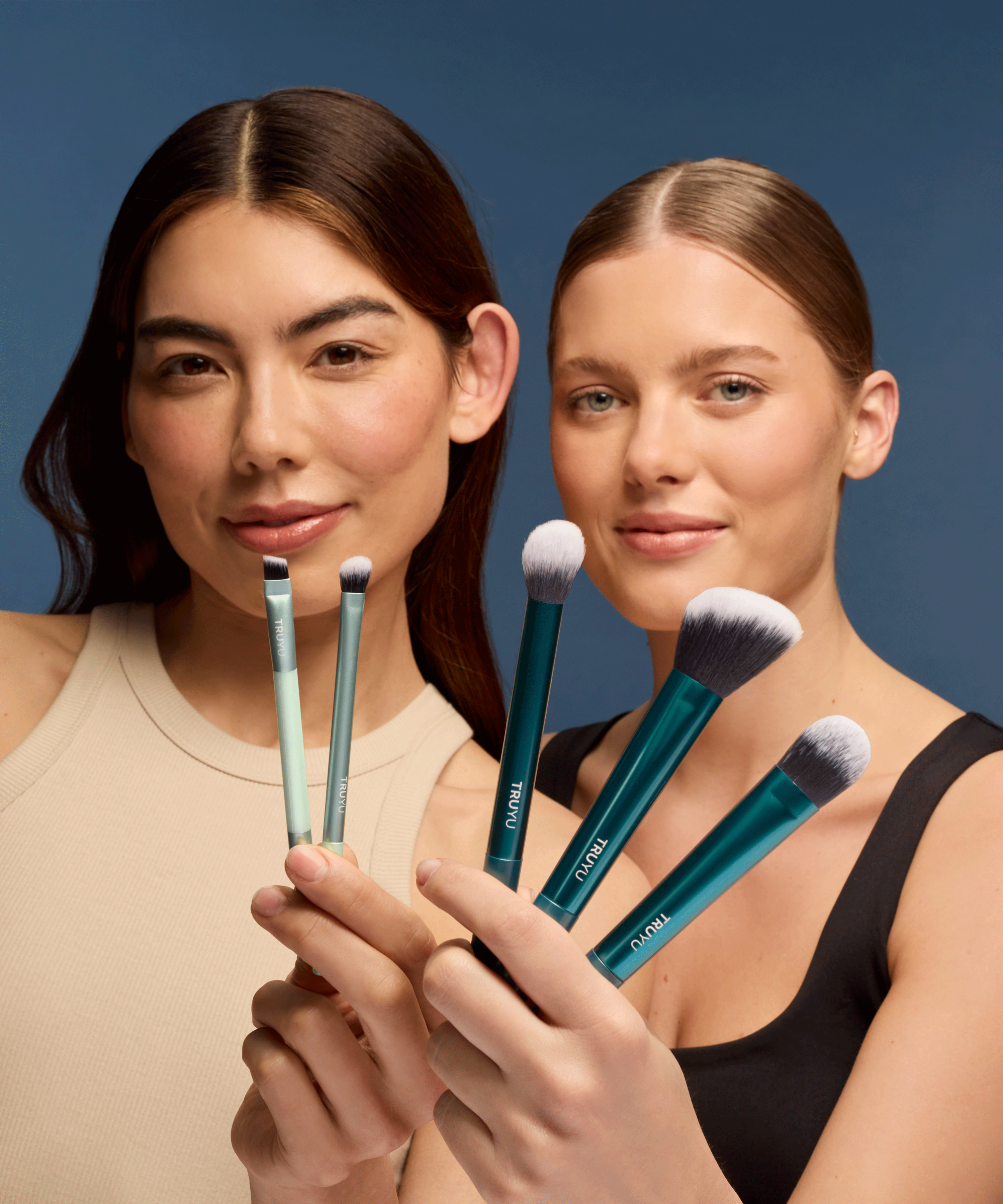 Two women models holding TRUYU Ultimate Brush Collection to camera. 