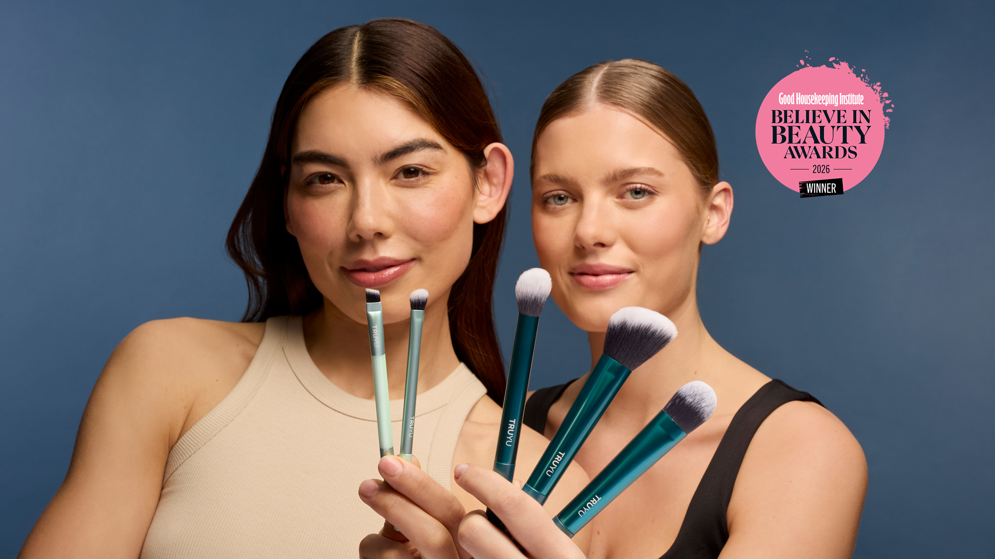 Two women holding makeup brushes with a 'Believe Beauty Awards' logo on a blue background