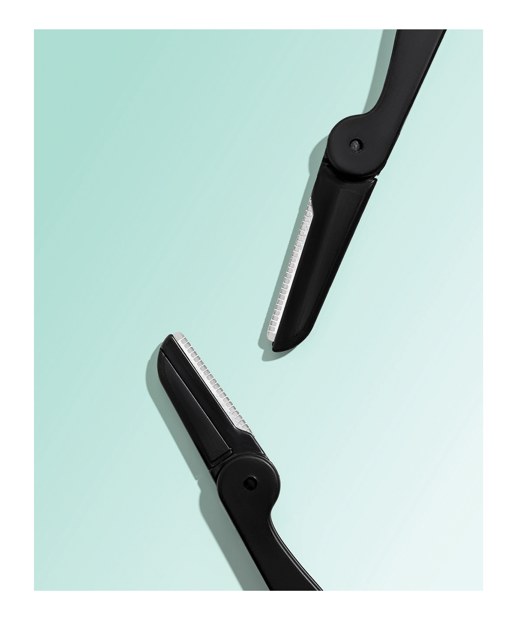 TRUYU Folding Facial Razors. Out of packaging. Close up image of 2 facial razor blades - one smaller brow blade, one larger facial blade. On mint coloured background.