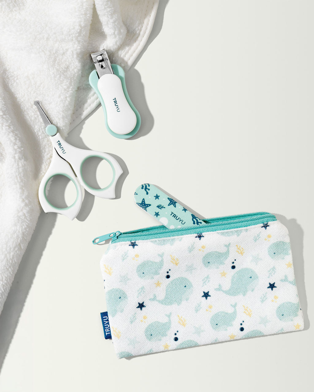 Baby Nail Set of nail clippers, scissors, nail file and a pouch with whale pattern, with white towel in corner.