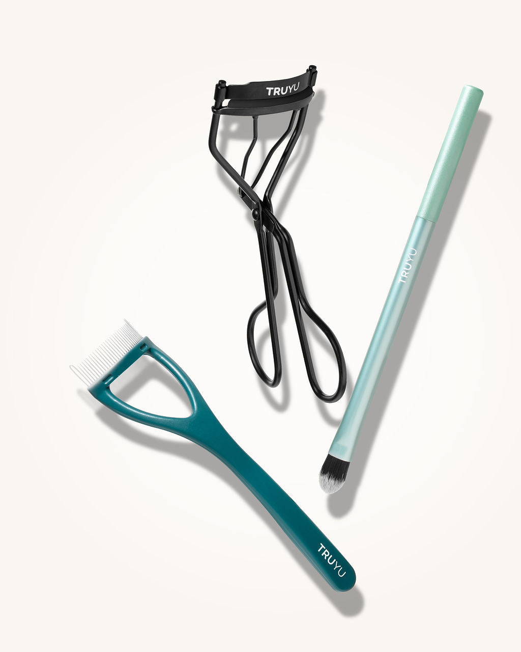 TRUYU Complete Eye Set out of pack. Including an eyelash curler, eyelash comb and eyeshadow brush on a cream background.