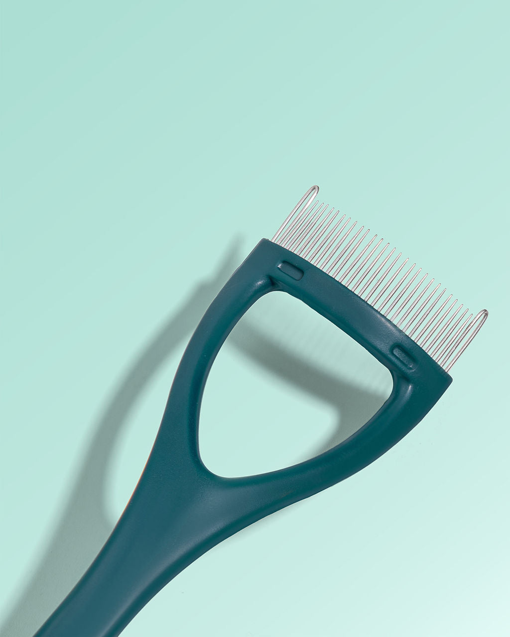 Close up image of metal bristles of TRUYU Eyelash Comb - on a light blue background.