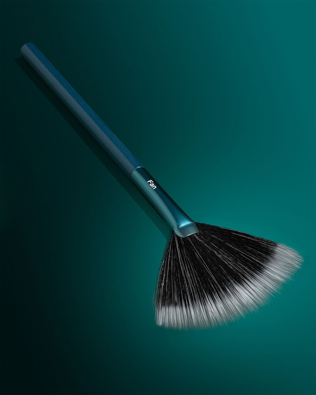 TRUYU Fan Brush out of packaging, on a teal background.