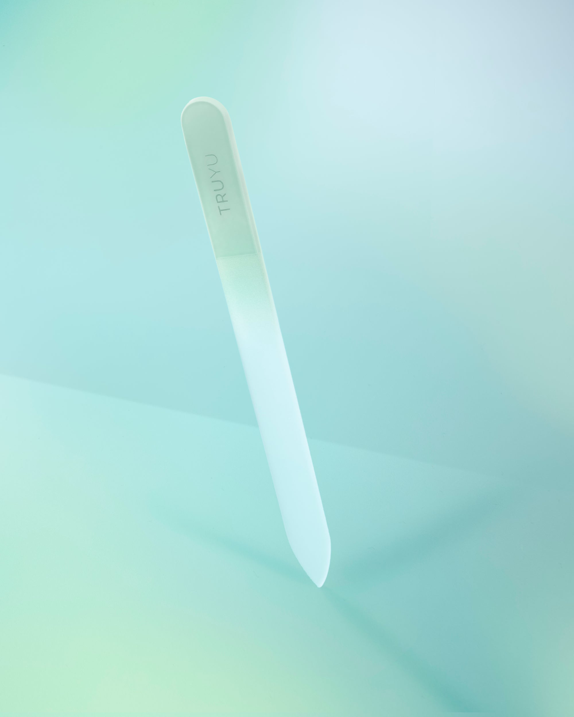 A translucent white plastic nail file with the brand name 'TRUYO' printed vertically on the upper section, set against a soft, light mint green gradient background.